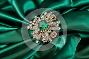 emerald brooch on green silk, centrally placed