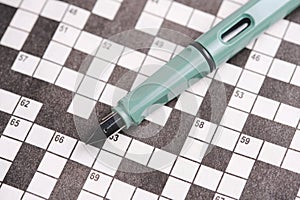 Emerald colored fountain pen lies on crosswords. Hobbies and mental memory.