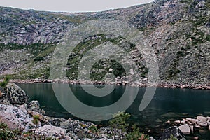 Emerald colored mountain lake surrounded by stones and coniferous trees