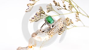 An emerald and diamond ring on a white background