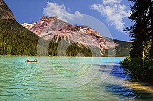 Emerald green lake, surrounded by coniferous forests and rocky m