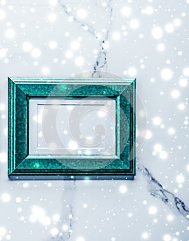 Emerald green photo frame and glowing glitter snow on marble flatlay background for Christmas and winter holidays