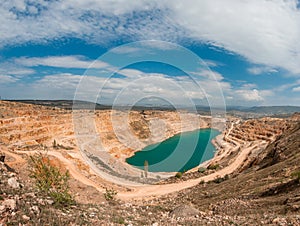 Emerald lake in a flooded quarry. Emerald green lake in flooded opencast mine, open pit. Oval lake in mining industrial crater,