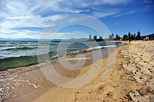 Emerald wave breaking on golden sand beach in Lake Tahoe