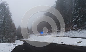 Emergency car with lights on winter road in the forest