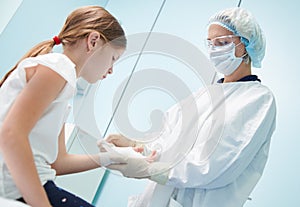 female surgeon doctor, in focus, bandaging child& x27;s hand in clinic