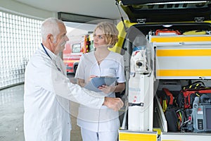 Emergency doctor and nurse standing in front ambulance car