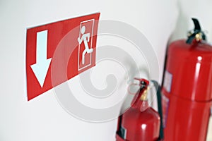 Emergency exit sign and fire extinguishers on wall, closeup