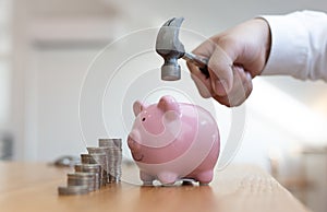 Emergency finance, Businessman using a hammer is about to destroy the pink piggy bank