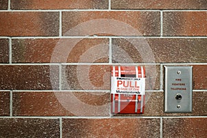 Emergency fire alarm switch on red brick wall background
