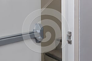 Emergency fire exit door. Closed up latch and rusty door handle of emergency exit. Push bar and rail for panic exit. Open one way