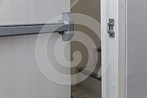 Emergency fire exit door. Closed up latch and rusty door handle of emergency exit. Push bar and rail for panic exit. Open one way