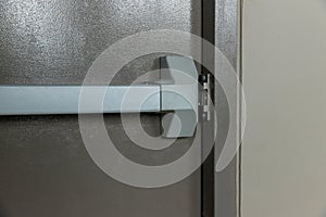 Emergency fire exit door. Closed up latch and rusty door handle of emergency exit. Push bar and rail for panic exit. Open one way