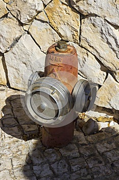 An emergency fire hydrant located in front of a stone wall in Albuferia in Portugal.