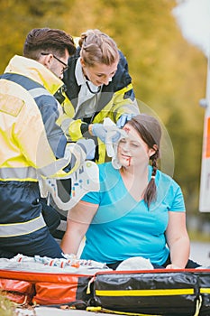 Emergency medics dressing head wound of injured woman