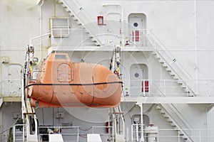 An emergency orange boat attaches to a large white ship.