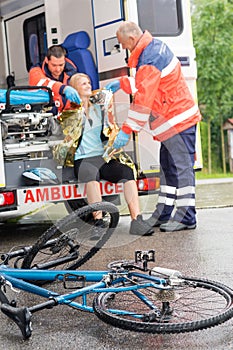 Emergency paramedics helping woman bike accident photo