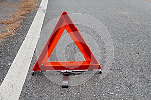 Emergency red warning triangle on the road sign with white traffic line