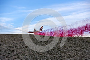 Emergency response airplane drops fire retardant over a wildfire going behind a desert hill with sagebrush