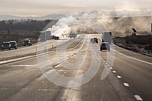 Emergency response vehicles lined up by a semi truck trailer fire on the side of a highway