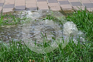 Emergency sewage. Water flows down the sidewalk from the sewer. An accident in the sewer.