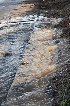 Emergency Sewerage. Water flows down the sidewalk from a ruptured underground sewer pipe. The accident of the city water supply. A