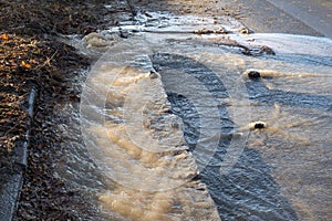 Emergency Sewerage. Water flows down the sidewalk from a ruptured underground sewer pipe. The accident of the city water supply. A