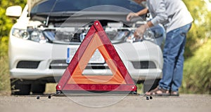 Emergency stop sign and driver near broken car on road