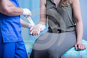 Emergency worker bandaging female hand