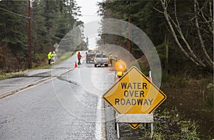 Emergency workers road crew placing warning signs on flooded highway. Hazards after a rain storm. photo