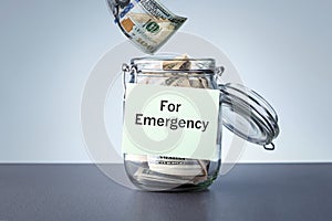 For Emergency written on a jar with dollars banknotes money