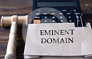 EMINENT DOMAIN - words on light brown paper against the background of a calculator and a judge\'s gavel photo