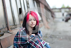 Emo girl sitting on a roof covered with a rug