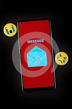 Emoji face and smartphone on black background.