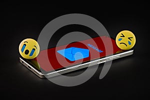 Emoji face and smartphone on black background.