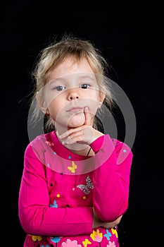 Emotion concept: pensive sad little girl. Black background, studio photo.