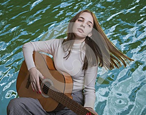 Emotion concept. Portrait of a young girl playing the guitar in front of the sea