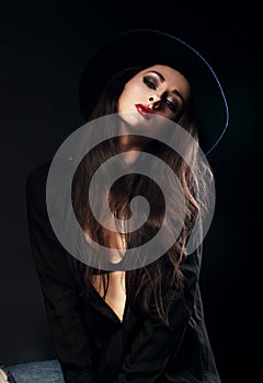 Emotion female model posing in black shirt and elegant hat