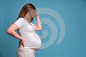 Emotion of worries and problems in a pregnant woman, studio shot on a blue background