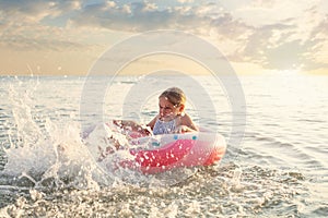 Emotional active little child girl splashing in the sea on a sunny summer during the holidays. The concept of family holidays with