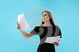 Emotional actress with script performing on light blue background. Film industry