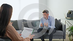 Emotional adult man patient with mental health problems talking to therapist