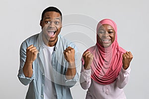 Emotional african american couple celebrating success, clenching fists and screaming