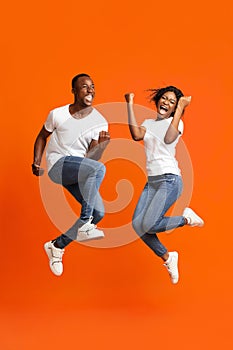 Emotional african american couple winners clenching fists and jumping up