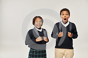 emotional african american schoolkids with backpacks