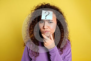 Emotional African-American woman with question mark sticker on forehead against background