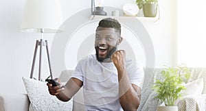 Emotional african soccer fan watching football on tv at home