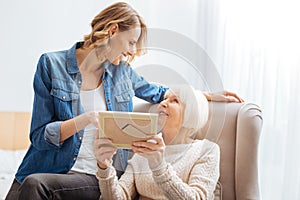 Emotional aged woman showing photos while being with her granddaughter