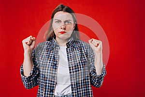 Emotional angry 30s woman screaming on red studio background. Emotional, young face. Screaming, hate, rage.