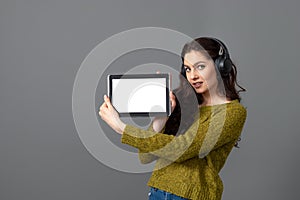 Emotional, attractive young woman showing tablet computer with empty touch screen with copy space